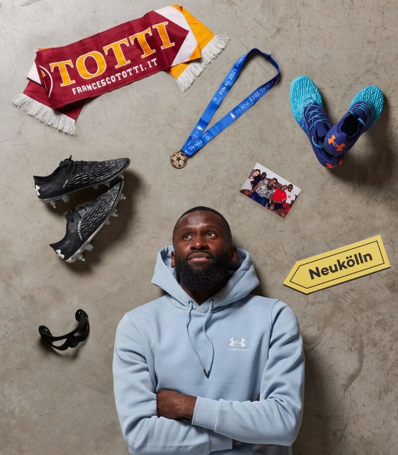 Footballer Antonia Rudiger lying down with football boots, medals and football scarf 